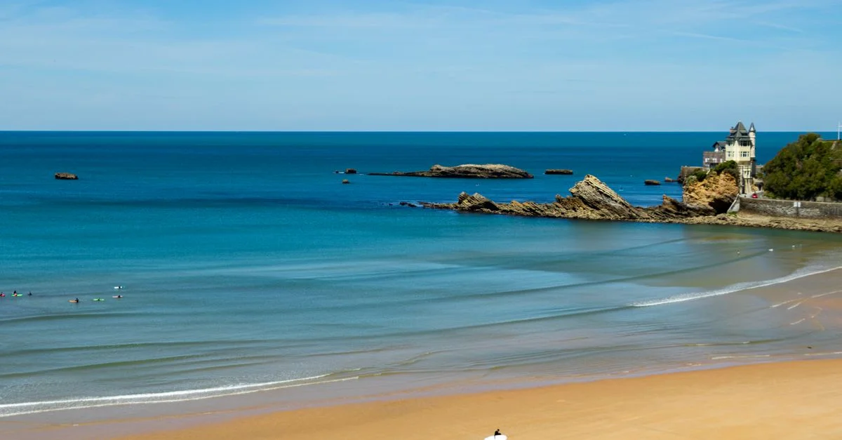 Belle vue sur la plage de la Côte des Basques à Biarritz, France avec des surfeurs et une eau bleue claire.
