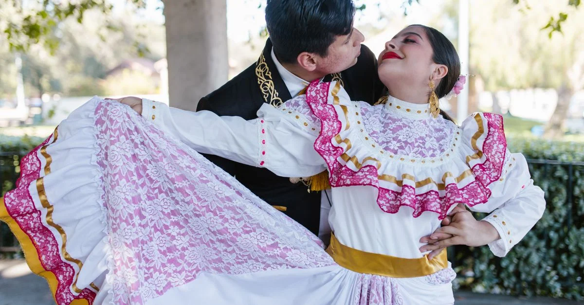 Un couple réalise une danse mexicaine traditionnelle en costumes éclatants en plein air.