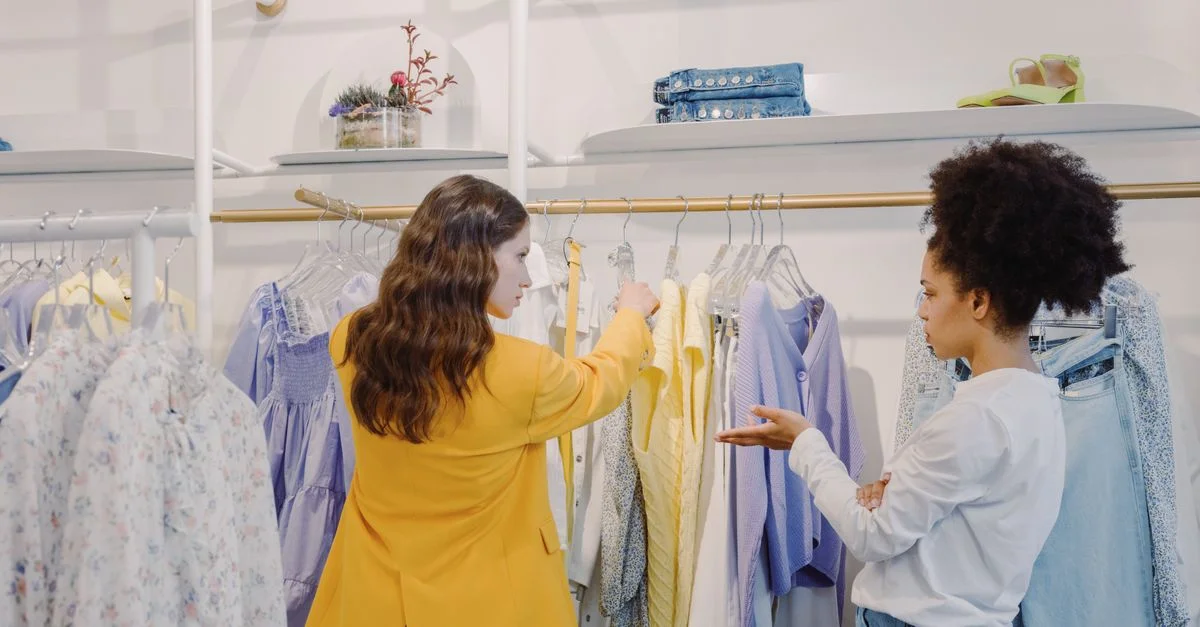 Deux femmes faisant du shopping dans une boutique élégante, explorant diverses options de mode.