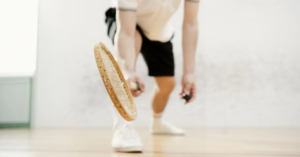 Gros plan sur un joueur de squash balançant sa raquette à l'intérieur avec un mouvement dynamique.